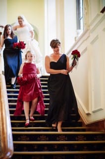 flower girl and bridesmaid walking downstairs in black and red dresses