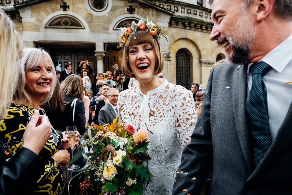 a bride with a bob haircut and autumnal orange flower crown and wildflower bouquet
